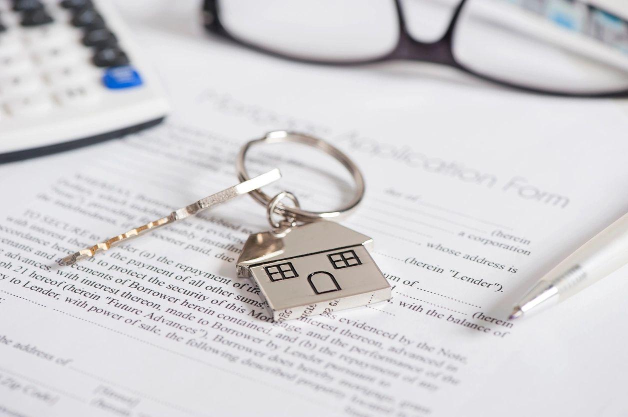 A calculator, spectacles, and a house key placed on a sheet of paper