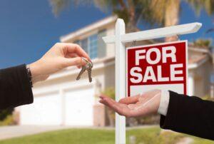 A person handing a key to a real estate agent, symbolizing the transfer of property ownership in a sale transaction