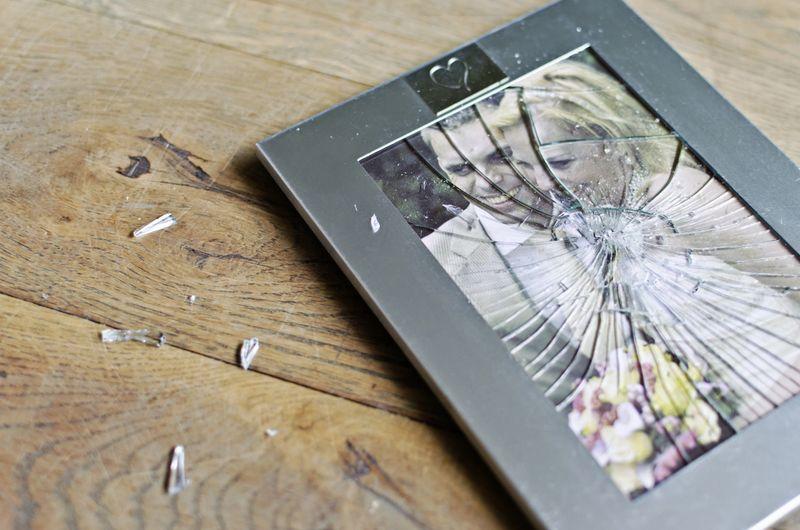 A broken picture frame displaying a photograph of a couple, symbolizing lost memories and fractured relationships