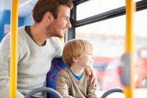 A man and a boy seated together on a bus, engaged in conversation.